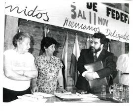 Sola Sierra hablando con un hombre en un lugar con banderas de fondo