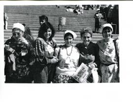 Grupo de mujeres con fotografías adheridas a sus ropas.